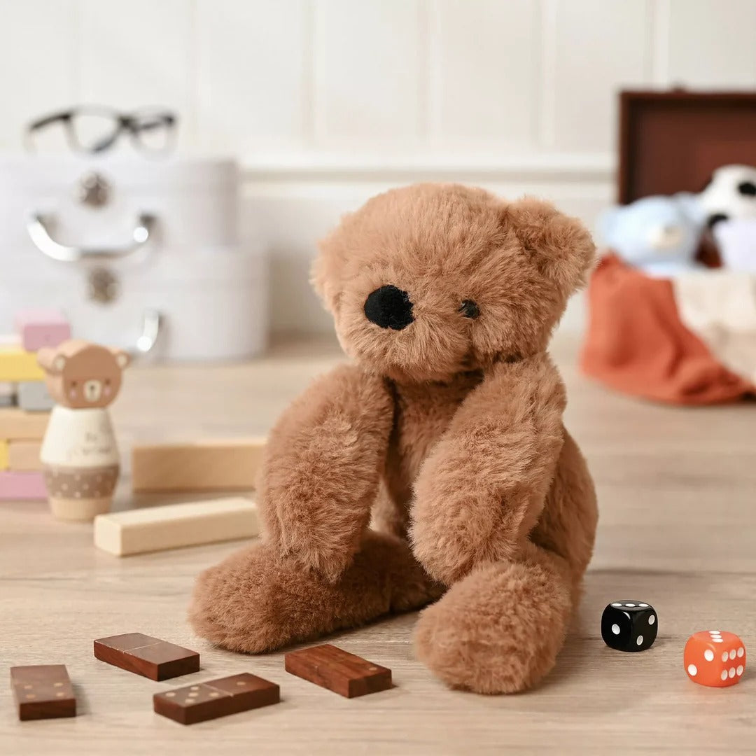 Brown teddy bear with dice and wooden blocks on a wooden surface