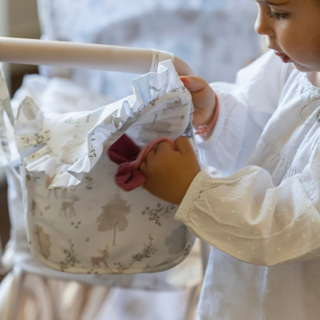 Child holding a baby bib with a floral pattern