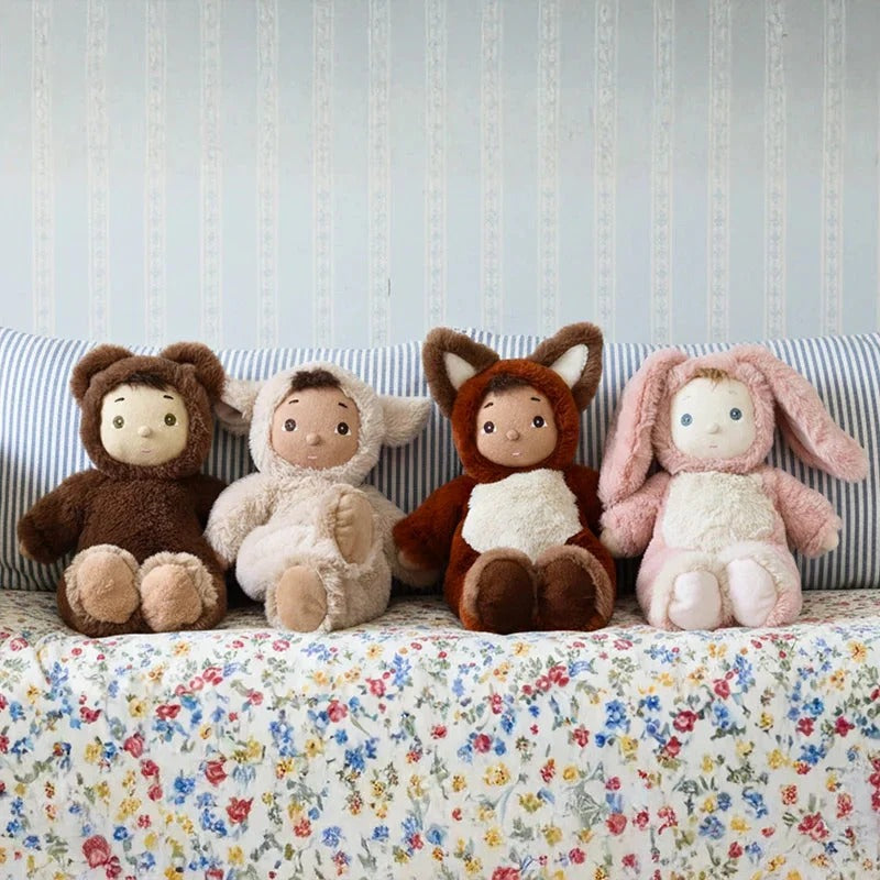 Four plush toys in animal costumes sitting on a floral-patterned surface with a striped background.