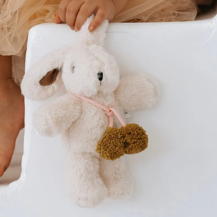 White plush dog toy with brown paws held by a child's hand on a white surface