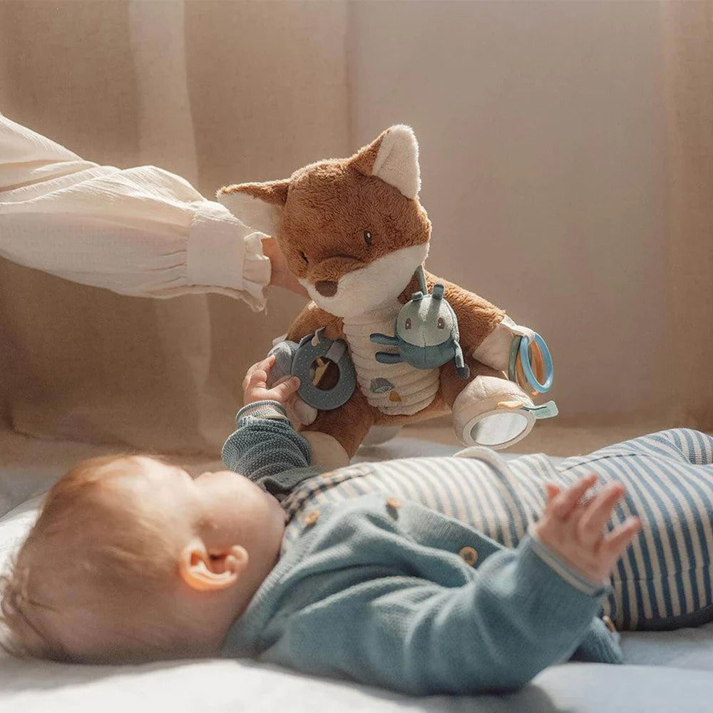 Baby playing with a plush fox toy on a soft surface