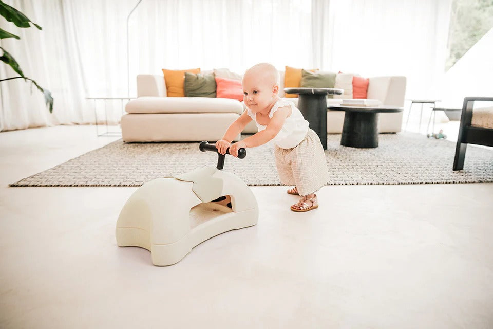 Baby riding a toy horse in a modern living room