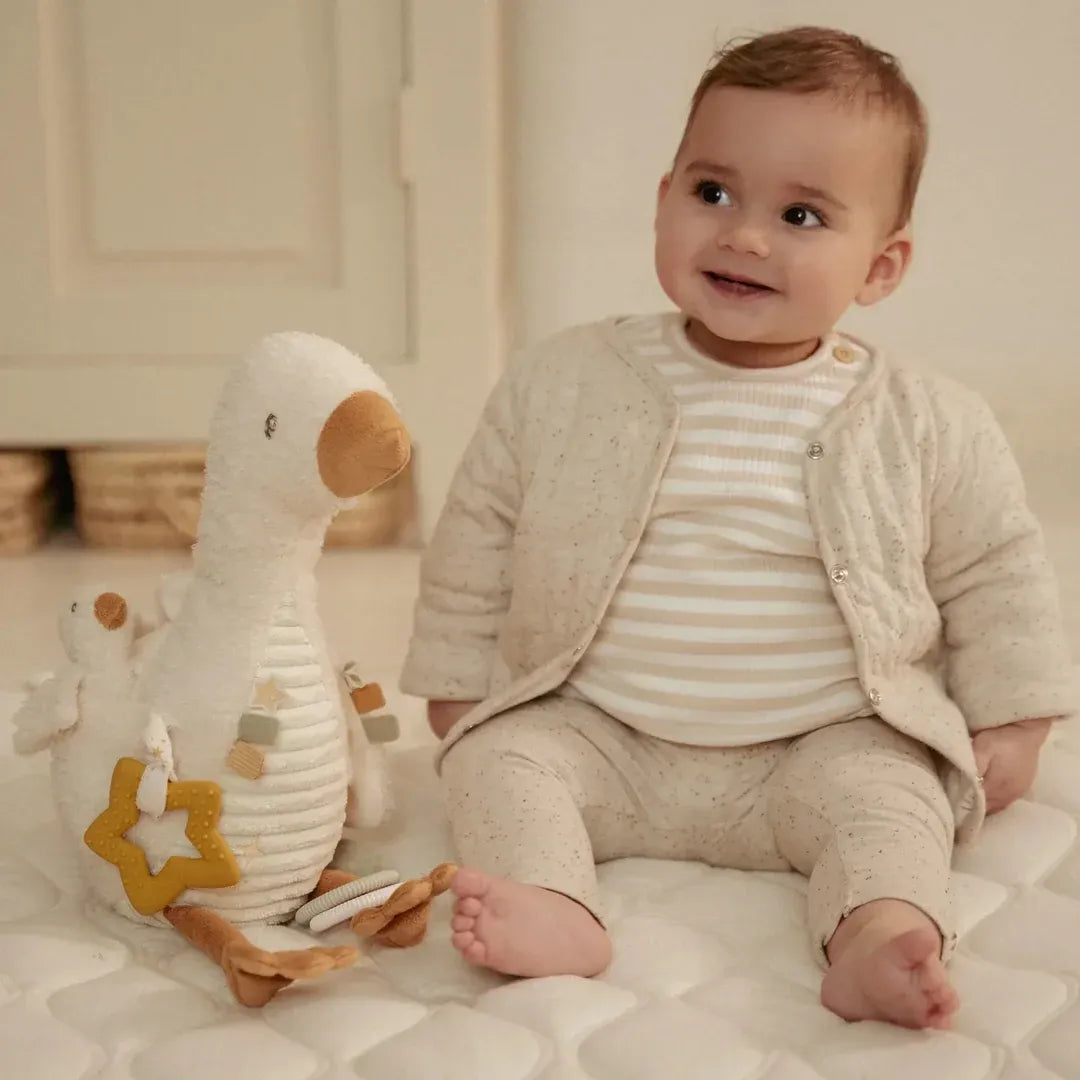 Baby sitting on a bed with a plush toy in a cozy room