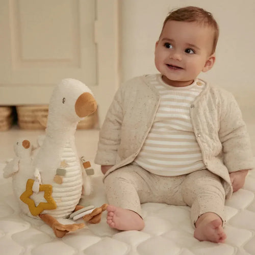 Baby sitting on a bed with a plush toy in a cozy room