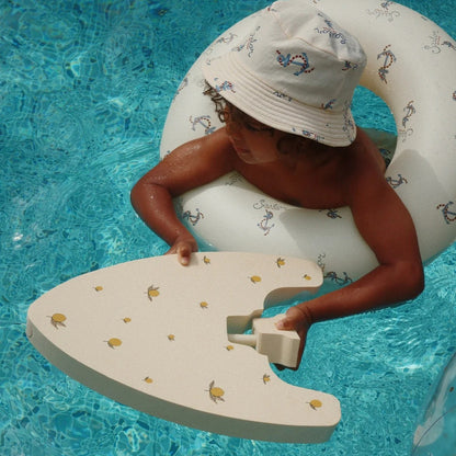 Child in a pool with a white inflatable ring and foam board
