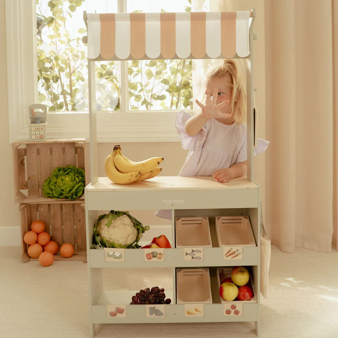 Child playing with a toy kitchen set in a bright room with a window.