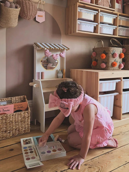 Child playing with a toy kitchen set in a playroom.