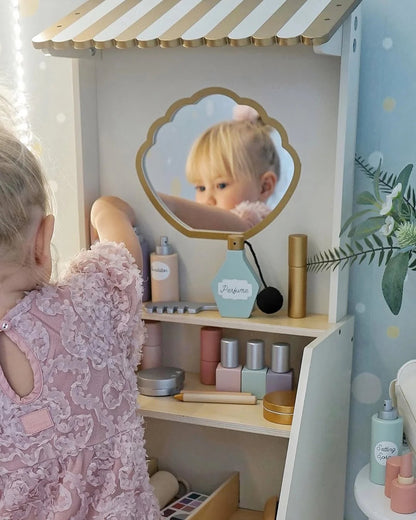 Child playing with a toy vanity set in a room with a polka dot wall.