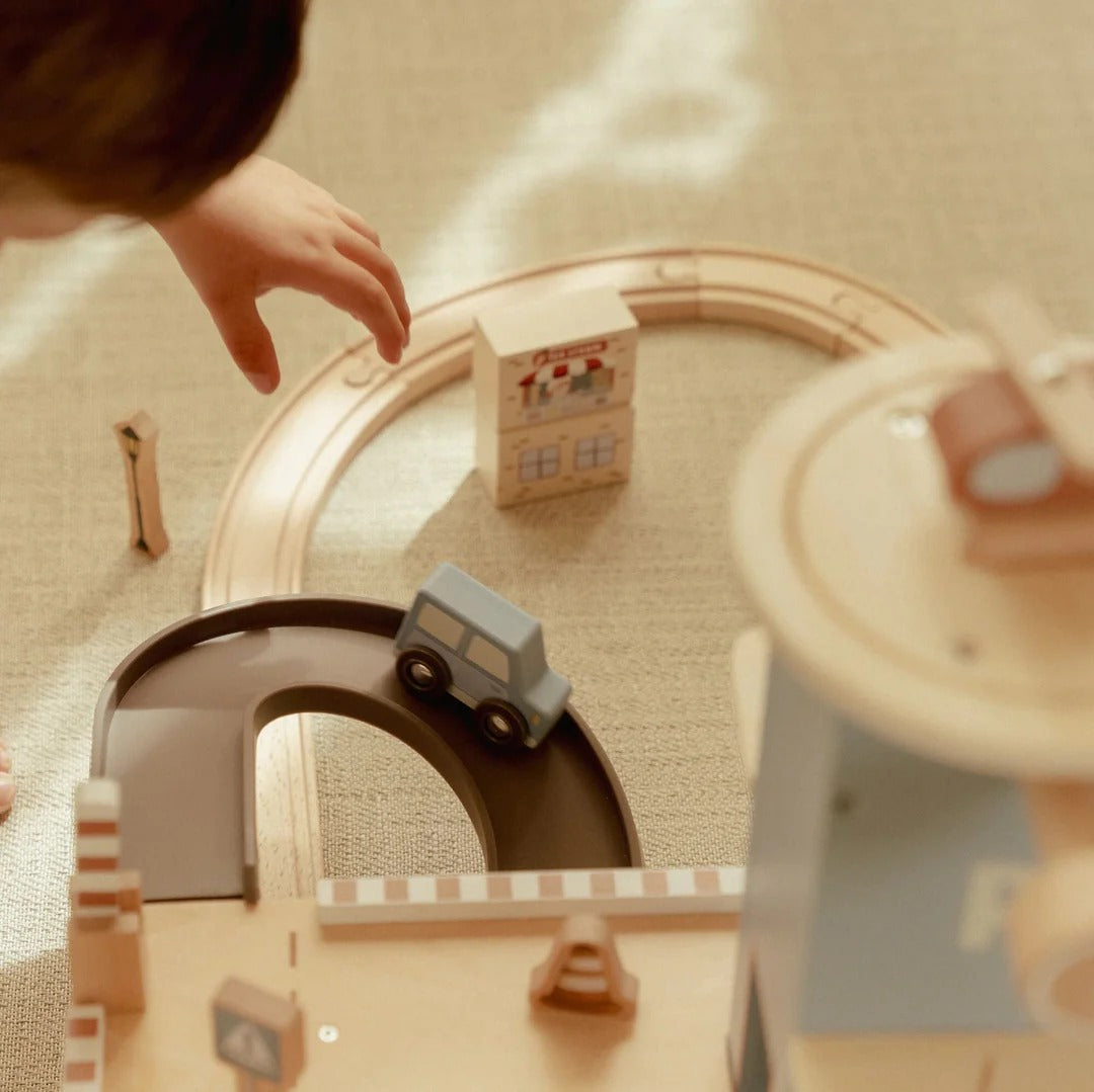 Children playing with a toy train set on a wooden floor