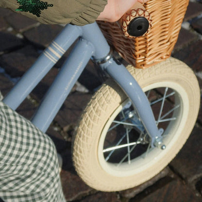 Children's balance bike with woven basket and wheels on a blurred background