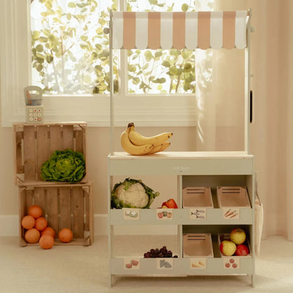 Children's play kitchen set with fruits and vegetables on a light background
