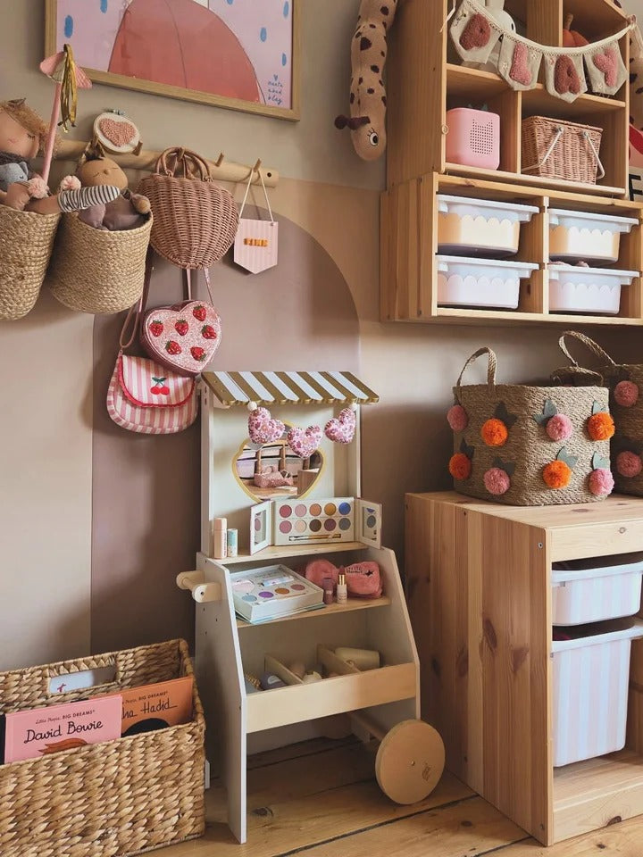 Children's playroom with wooden toys, storage bins, and decorative elements.