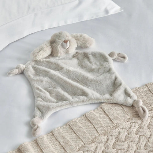 Fluffy blanket with bunny ears and tail on a textured surface