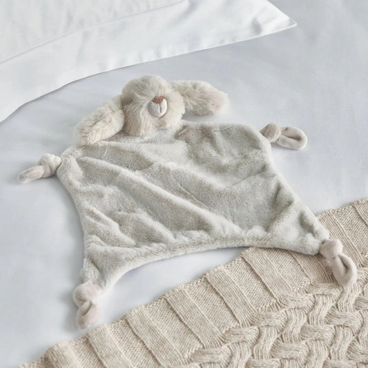 Fluffy blanket with bunny ears and tail on a textured surface