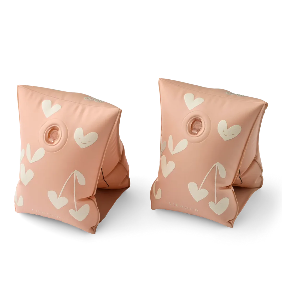 Pair of pink inflatable arm floats with heart patterns on a white background
