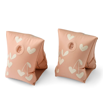 Pair of pink inflatable arm floats with heart patterns on a white background