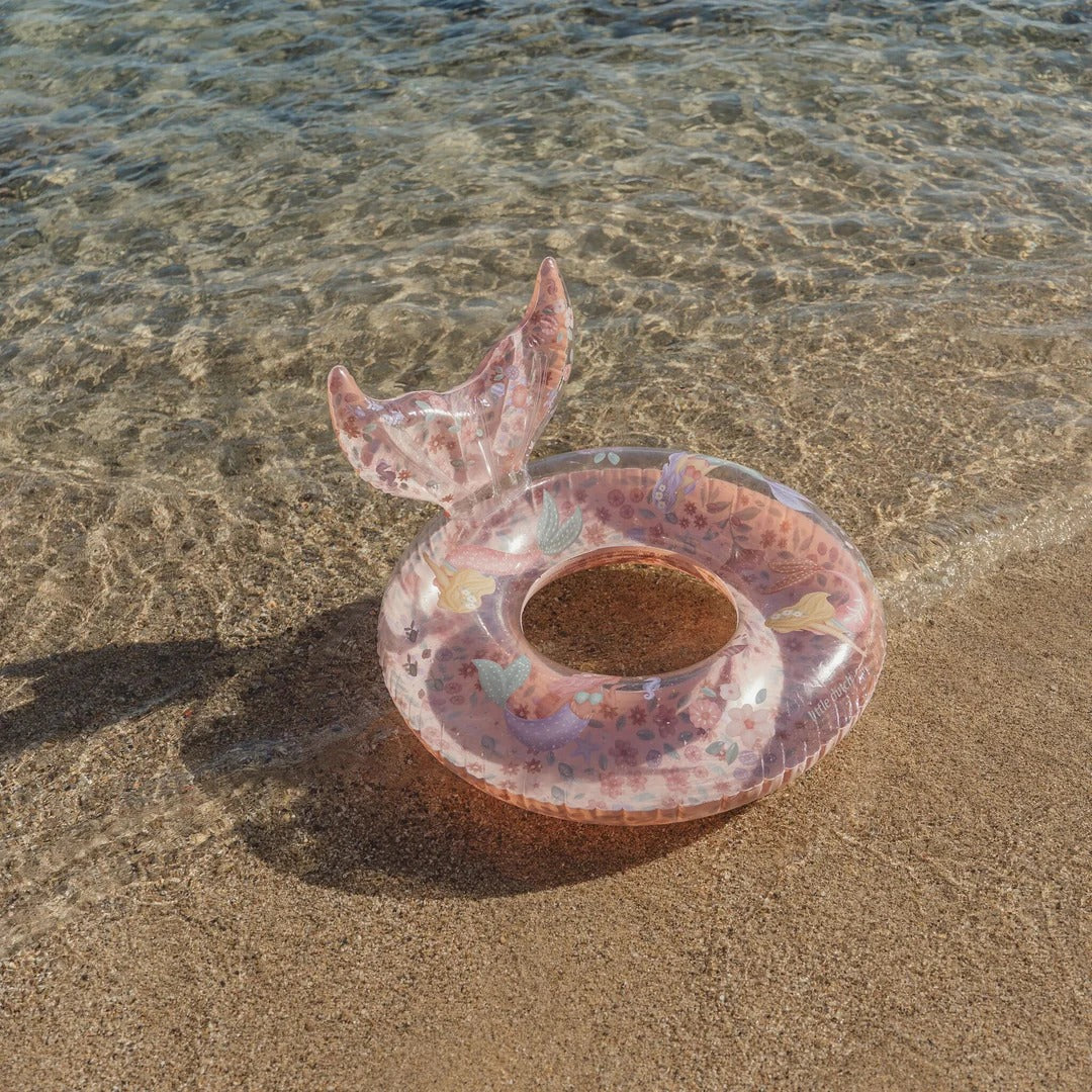 Pink inflatable ring with a tail on a sandy beach