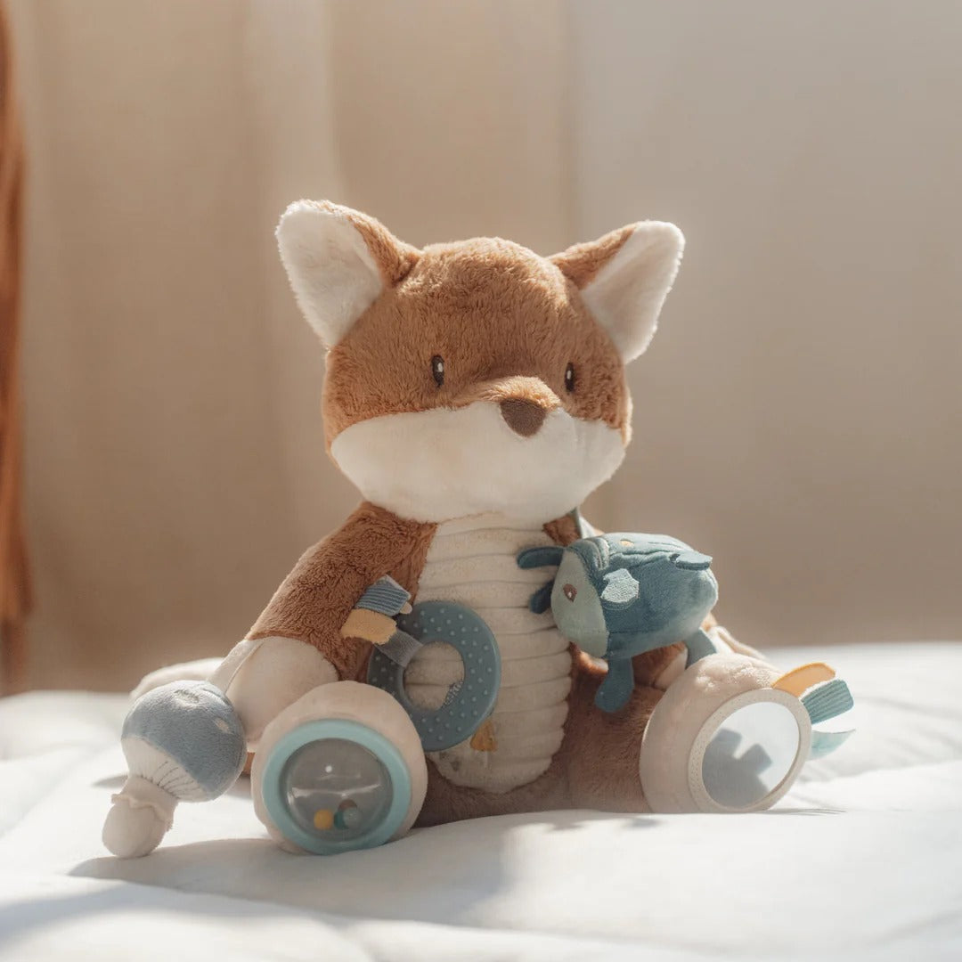 Plush toy fox with a bicycle on a soft surface