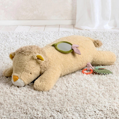 Plush toy resembling a lion with a mirror and rattle on a carpeted floor.