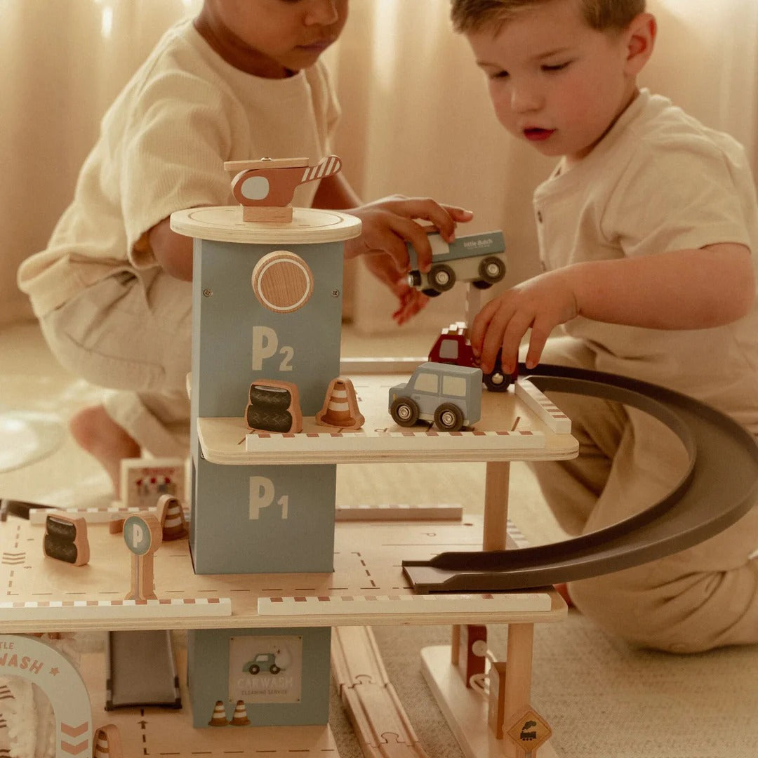 Two children playing with toy cars on a wooden track set.