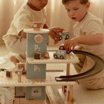 Two children playing with toy cars on a wooden track set.