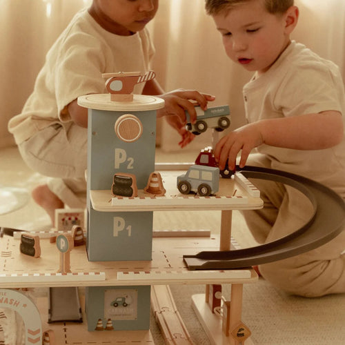 Two children playing with toy cars on a wooden track set.