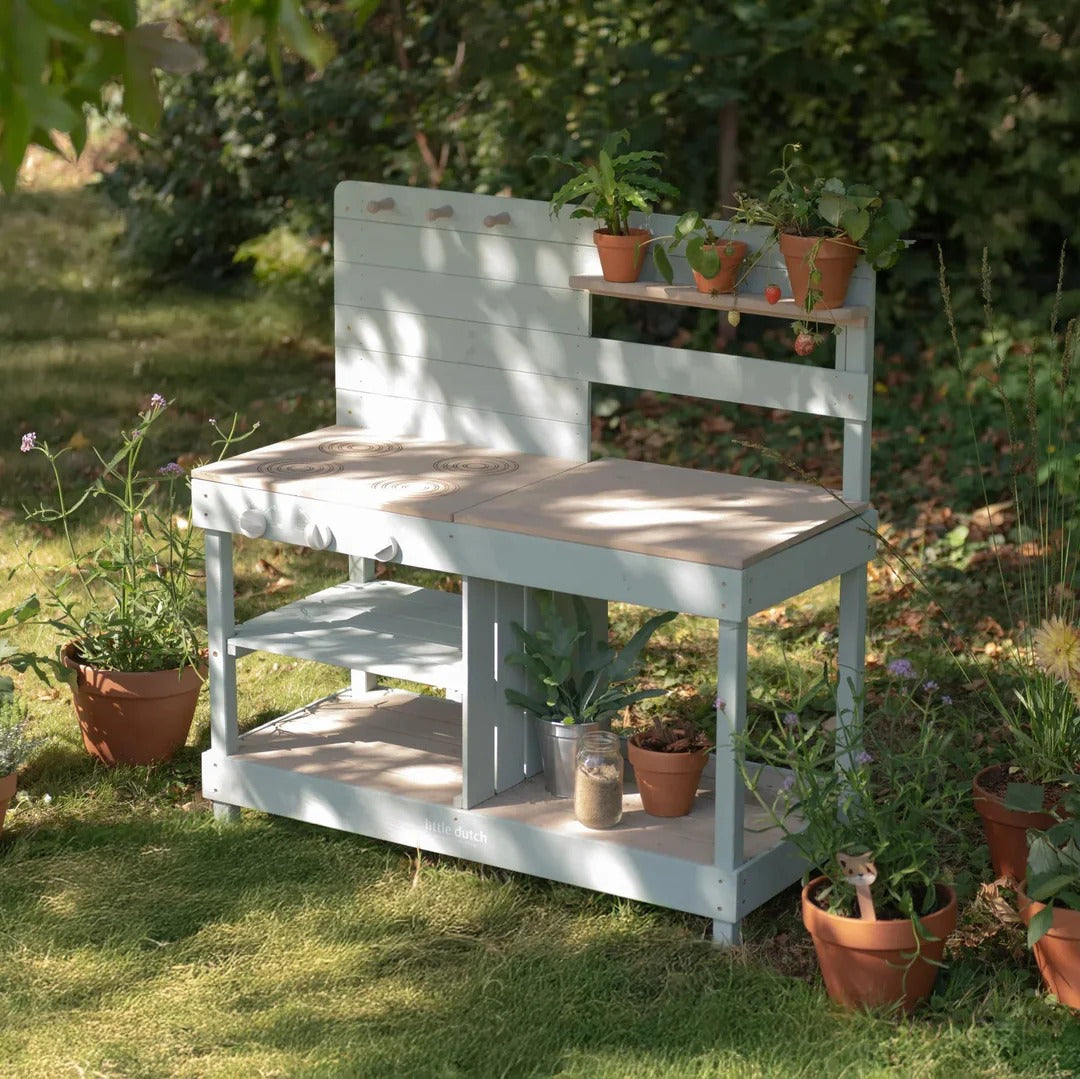 White garden bench with shelves and potted plants in a garden setting