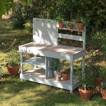 White garden bench with shelves and potted plants in a garden setting