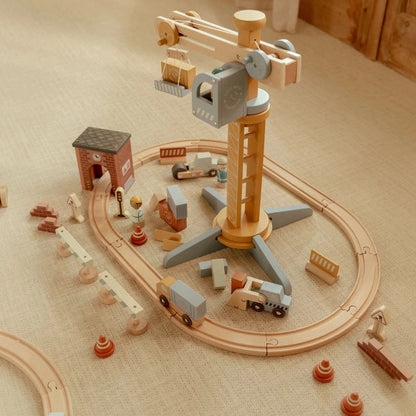 Wooden toy construction set with crane and various vehicles on a beige surface